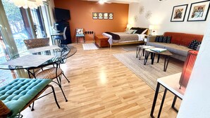 Ein modernes Wohnzimmer mit einem Glastisch, einer Couch, einem Bett und einem Fernseher.