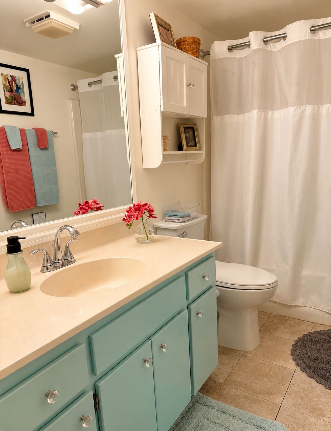 A bathroom with a sink, mirror, toilet, and shower curtain.