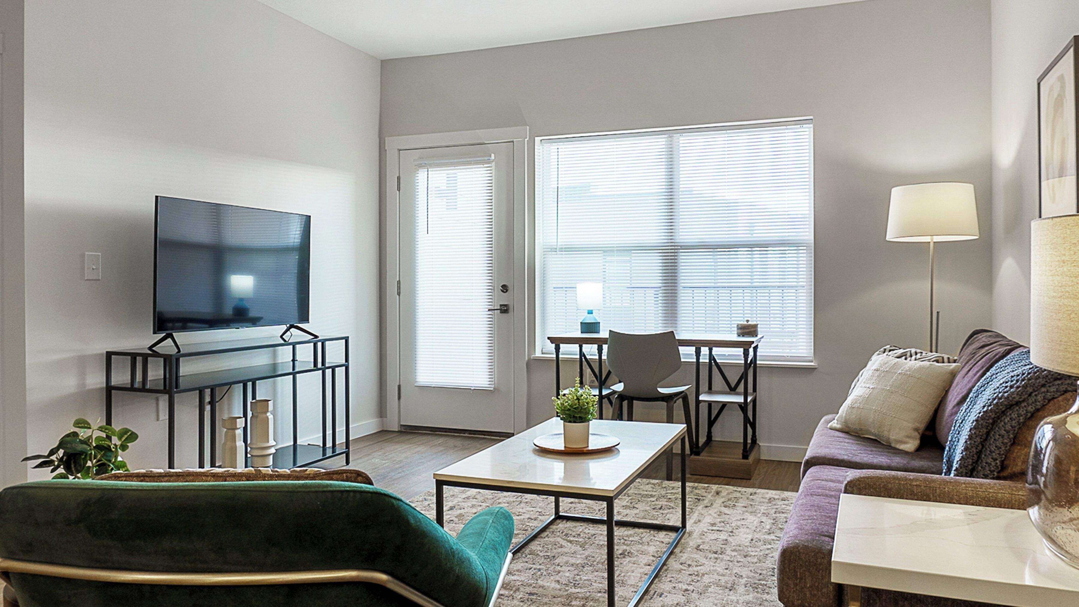 Ein Wohnzimmer mit Fernseher, einer Couch, einem Couchtisch und einem Essbereich mit Tisch und Stühlen.