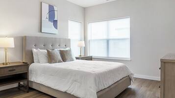 Un dormitorio moderno con una cama grande, dos mesitas de noche y un cuadro colgado en la pared.