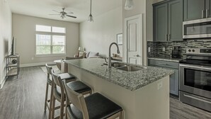 Una cocina moderna con encimera de granito, electrodomésticos de acero inoxidable y una zona de bar con taburetes.