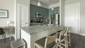 Una cocina moderna con encimeras de granito, electrodomésticos de acero inoxidable y armarios color aguamarina.