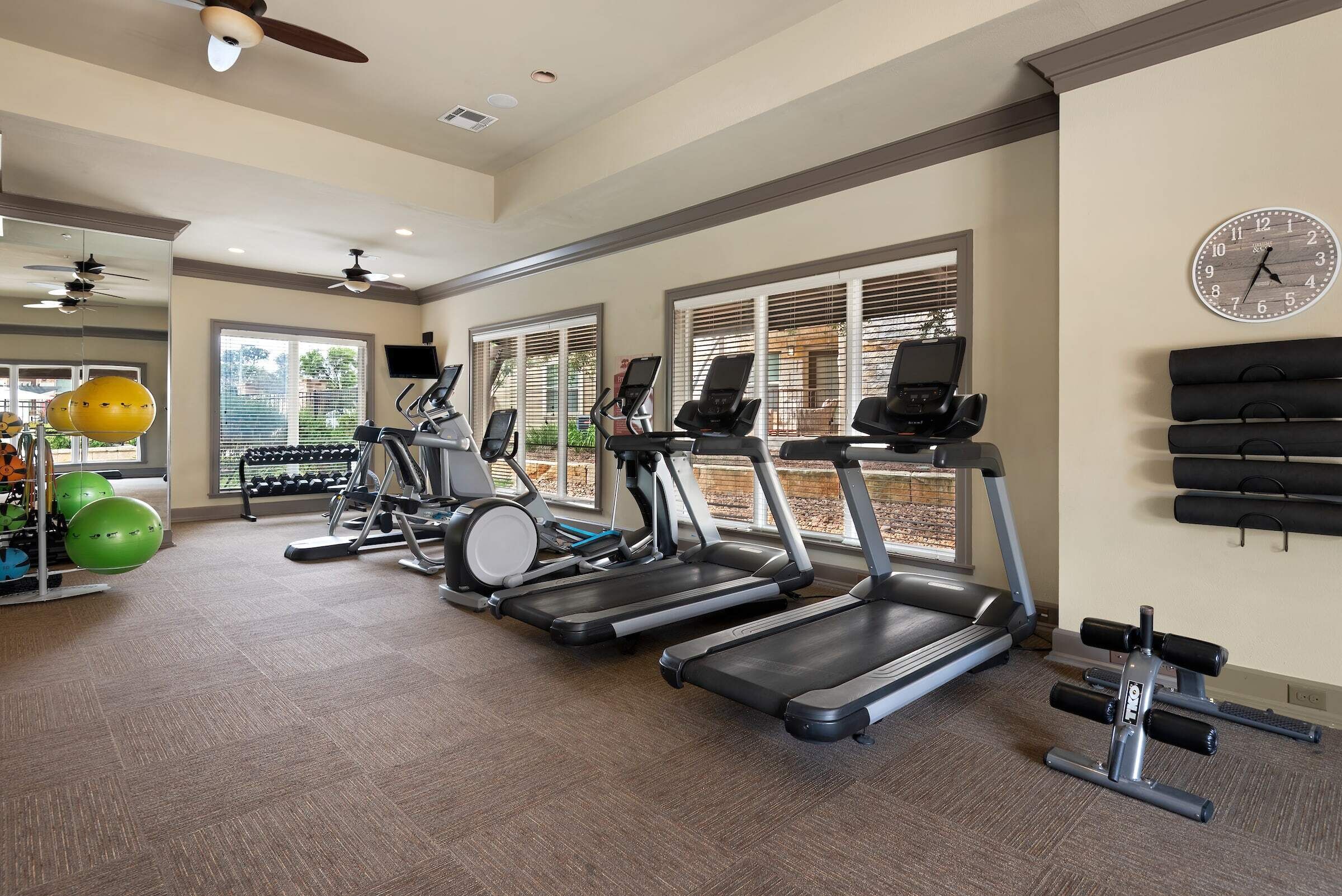 A gym with treadmills, stationary bikes, and exercise balls.