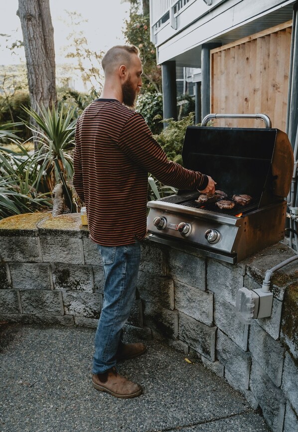 A person grilling outdoors with a stone-built barbecue.