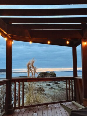 A wooden deck with a view of a rocky shoreline and a body of water.