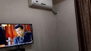 A television mounted on a wall with a remote control below it. - 116 Business Hostel (Chongqing)