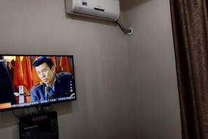 A television mounted on a wall with a remote control below it. - 116 Business Hostel (Chongqing)