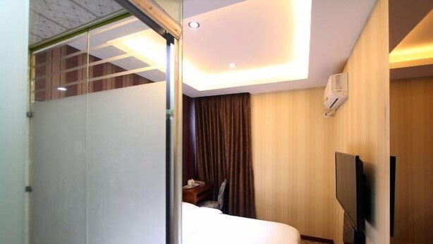 A hotel room with a bed, a TV mounted on the wall, and an air conditioning unit. - 116 Business Hostel (Chongqing)