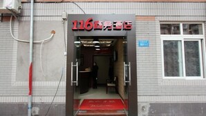 A hotel entrance with a red carpet and a sign displaying the number 116. - 116 Business Hostel (Chongqing)