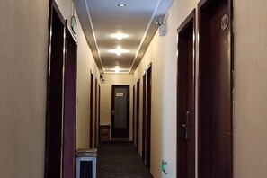 A hotel hallway with doors on both sides, a trash bin, and a light switch on the wall. - 116 Business Hostel (Chongqing)
