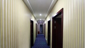 A hotel corridor with a blue carpet, beige walls, and wooden doors. - 116 Business Hostel (Chongqing)