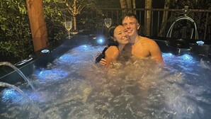 Un jacuzzi con dos personas, rodeado de bambú y otras plantas tropicales.