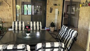 Un comedor con mesa de vidrio, sillas a rayas y vistas al exterior a través de un ventanal.