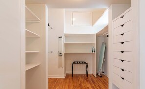 A walk-in closet with white shelving, a small bench, and a hanging rack. - DAM Arquim20 (Mexico City)
