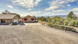 A residential property with a gravel driveway, a wooden fence, and a house with a red awning. - Vacation Home With Breathtaking Views, Ample Parking and Pool Table (Cañon City)