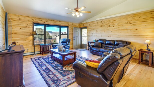 A spacious living room with a large leather sofa, a wooden coffee table, and a ceiling fan. - Vacation Home With Breathtaking Views, Ample Parking and Pool Table (Cañon City)