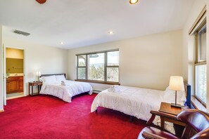 A hotel room with two beds, a red carpet, a wooden nightstand, a lamp, and a window with a view. - Vacation Home With Breathtaking Views, Ample Parking and Pool Table (Cañon City)