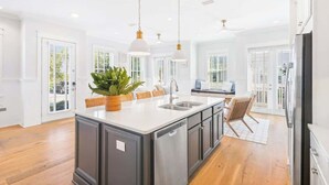 A modern kitchen with a central island, pendant lighting, and a view to the outside. - 30A Seaside Escape by Stay on 30a (Inlet Beach)
