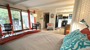 Een slaapkamer met een groot bed, een bureau, een stoel en uitzicht op de keuken.