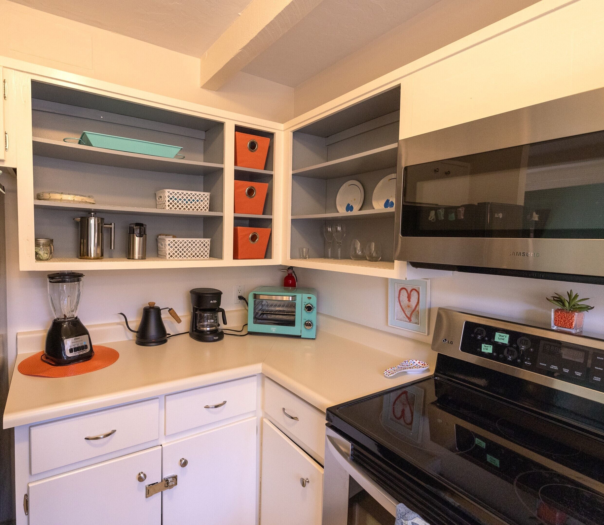 A kitchen with white cabinets, a black stove, a teal toaster, and a coffee maker.