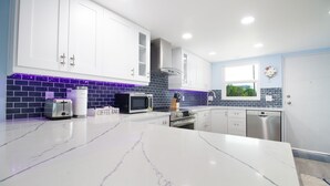 A modern kitchen with white cabinets, a marble countertop, a microwave, a toaster, and a coffee machine. - Intracoastal Waterways / Dolphin Sighting / YTC Resort (Indian Shores)