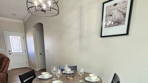 A dining area with a round table set for four, surrounded by four chairs. A modern chandelier hangs above the table. - Cupcake Mtn. View Tranquility (Lake Havasu City)