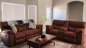 A modern living room with two brown leather sofas, a wooden coffee table, and a ceiling fan. - Cupcake Mtn. View Tranquility (Lake Havasu City)