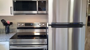 Una cucina con elettrodomestici in acciaio inossidabile, tra cui un forno a microonde, forno e frigorifero.
