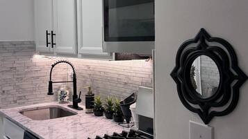A kitchen with white cabinets, a stainless steel stove, a black faucet, and a microwave.
