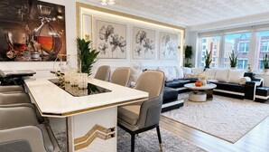 A modern living room with a dining area, featuring a central island, seating, and artwork on the walls. - Spacious 4-bedroom apartment in Manhattan with Doorman (New York)