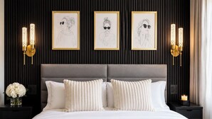 A bedroom with a large bed, two wall-mounted sconces, and three framed artworks on the wall. - Spacious 4-bedroom apartment in Manhattan with Doorman (New York)