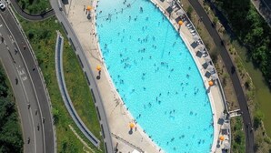 An aerial view of a swimming pool with a surrounding walkway, adjacent roads, and greenery. - Spacious 4-bedroom apartment in Manhattan with Doorman (New York)
