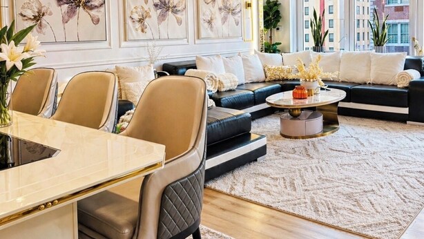 A modern living room with a sofa, chairs, a dining table, and artwork on the wall. - Spacious 4-bedroom apartment in Manhattan with Doorman (New York)