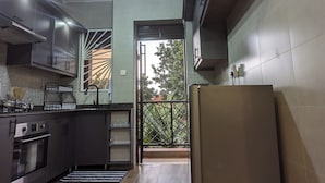 A modern kitchen with stainless steel appliances, a patterned backsplash, and a view of the outdoors through a sliding door.
