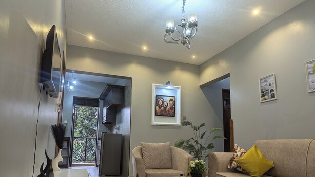 A living room with a sofa, a coffee table, and a TV on a stand. There is a chandelier hanging from the ceiling.