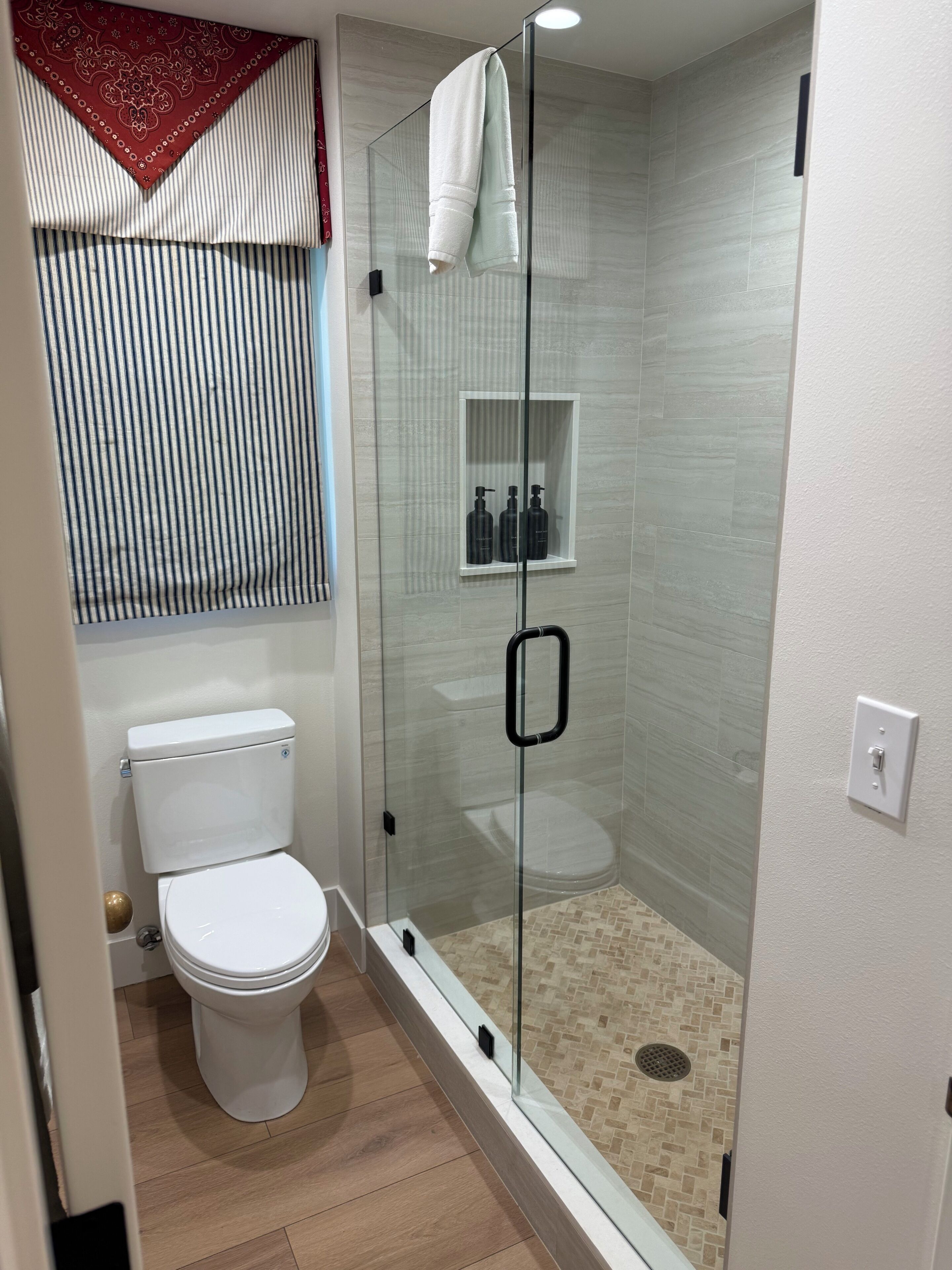 Un baño moderno con ducha de vidrio, inodoro y tocador con espejo.