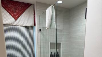 Un baño moderno con ducha de vidrio, inodoro y tocador con espejo.