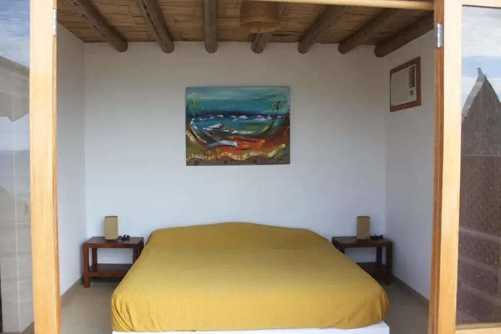 Une chambre avec un lit, un tableau au mur et deux tables de chevet.