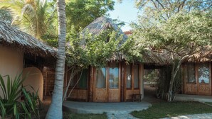 Alojamiento de estilo bungalow con techos de paja, puertas de madera y un camino pavimentado.