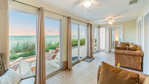 Amplia habitación con grandes puertas corredizas de vidrio que dan a un balcón, ventilador de techo y sofá con cojines.