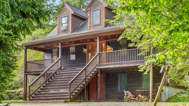 A two-story wooden cabin with a porch, a staircase, and a deck. - The Getaway: Relax with hot tub, fire pit, and mountain views—just 15 mins from Killington slopes! (Pittsfield)