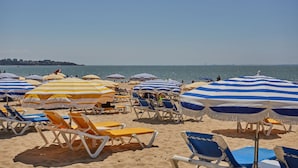 Una playa con filas de tumbonas y sombrillas a rayas.