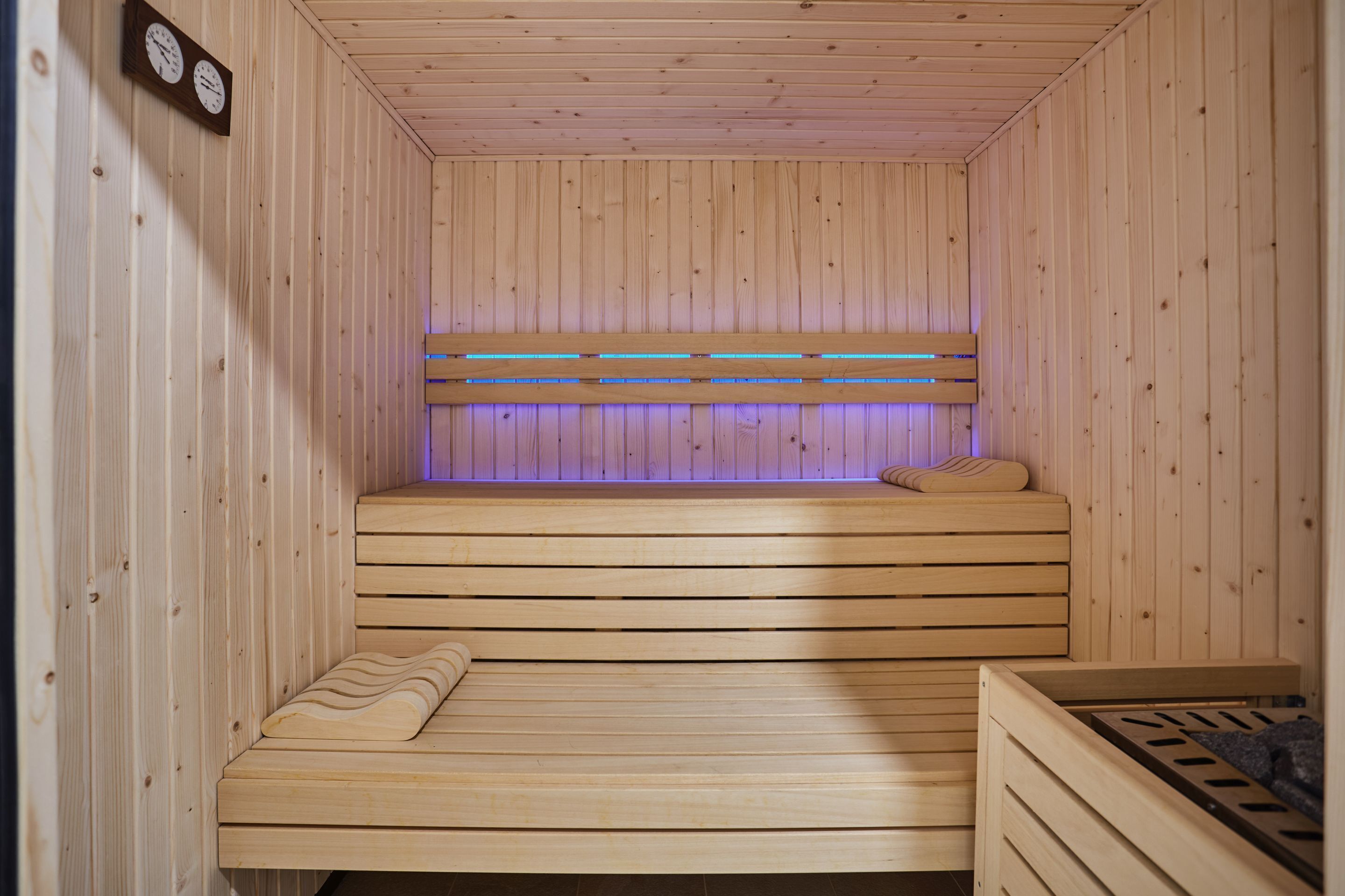 Un sauna en bois avec un banc, un banc au design ondulé et un cadre de lit.