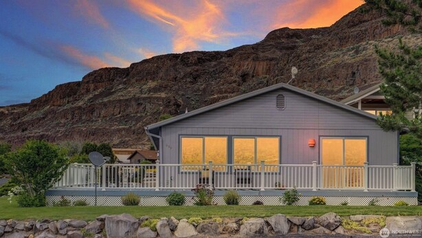 Une maison à deux étages dotée d’un balcon, située dans un cadre montagneux.