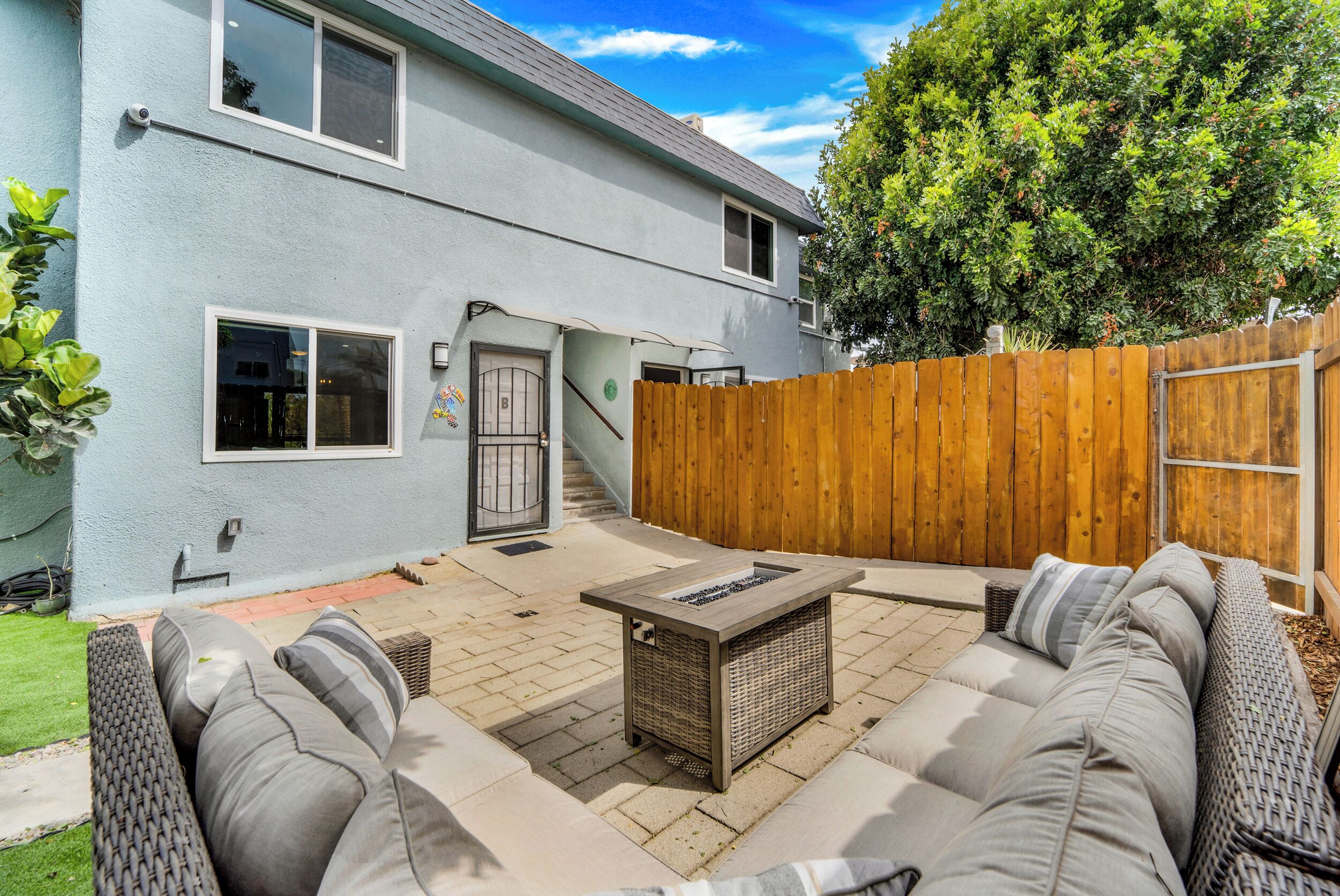 A backyard with a patio, outdoor furniture, and a wooden fence.
