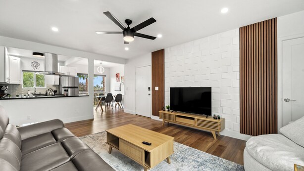 A modern living room with a sofa, coffee table, TV, and wooden accents. - Delightful & Comfy 2-Bedroom in Ocean Beach with BBQ Grill (San Diego)