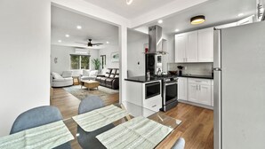 A modern kitchen with white cabinets, a stainless steel range hood, and a built-in oven. - Delightful & Comfy 2-Bedroom in Ocean Beach with BBQ Grill (San Diego)
