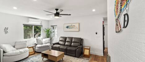 A modern living room with a brown leather sofa, a white armchair, and a wooden coffee table.
