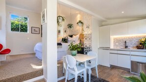 Une cuisine moderne avec des meubles blancs, un réfrigérateur en acier inoxydable et un coin repas comprenant une table et des chaises.