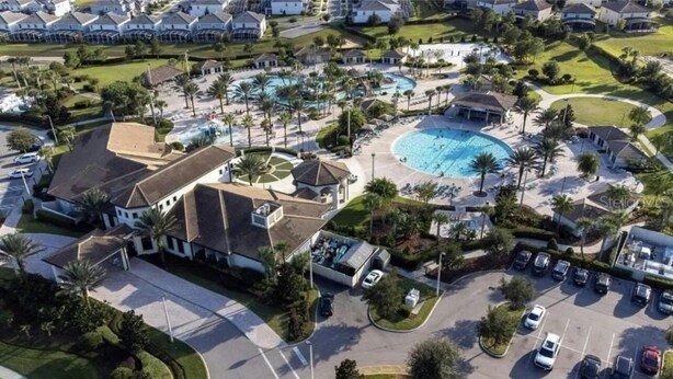 Vista aérea de una zona residencial con una piscina grande, varias casas y un estacionamiento.